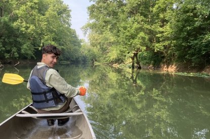 Wildlife conservation student Whit sits in canoe at Ohio Preserve Lake Katharine.