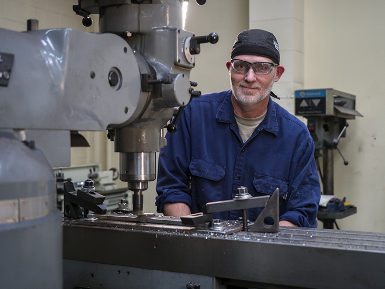 welding student in blue sits at machine