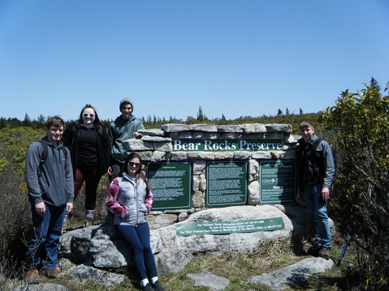 Students stand at Bear Rock Sign