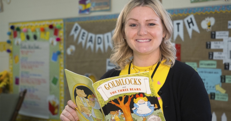 Student smiling with children's book