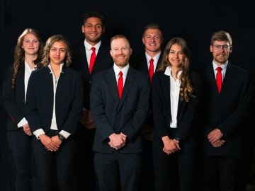 2023 American Marketing Students pose in dark suits with professor Thoene