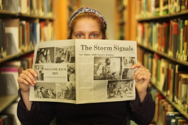 Students poses in library with Storm Signals newspaper