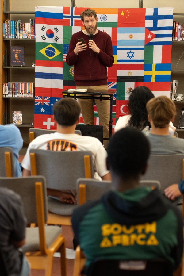 Male student reading to audience at Words of the World Event